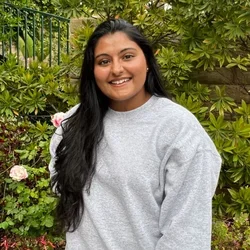 Rida Ismail standing in front of bushes smiling