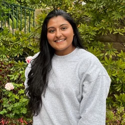 Rida Ismail standing in front of bushes smiling